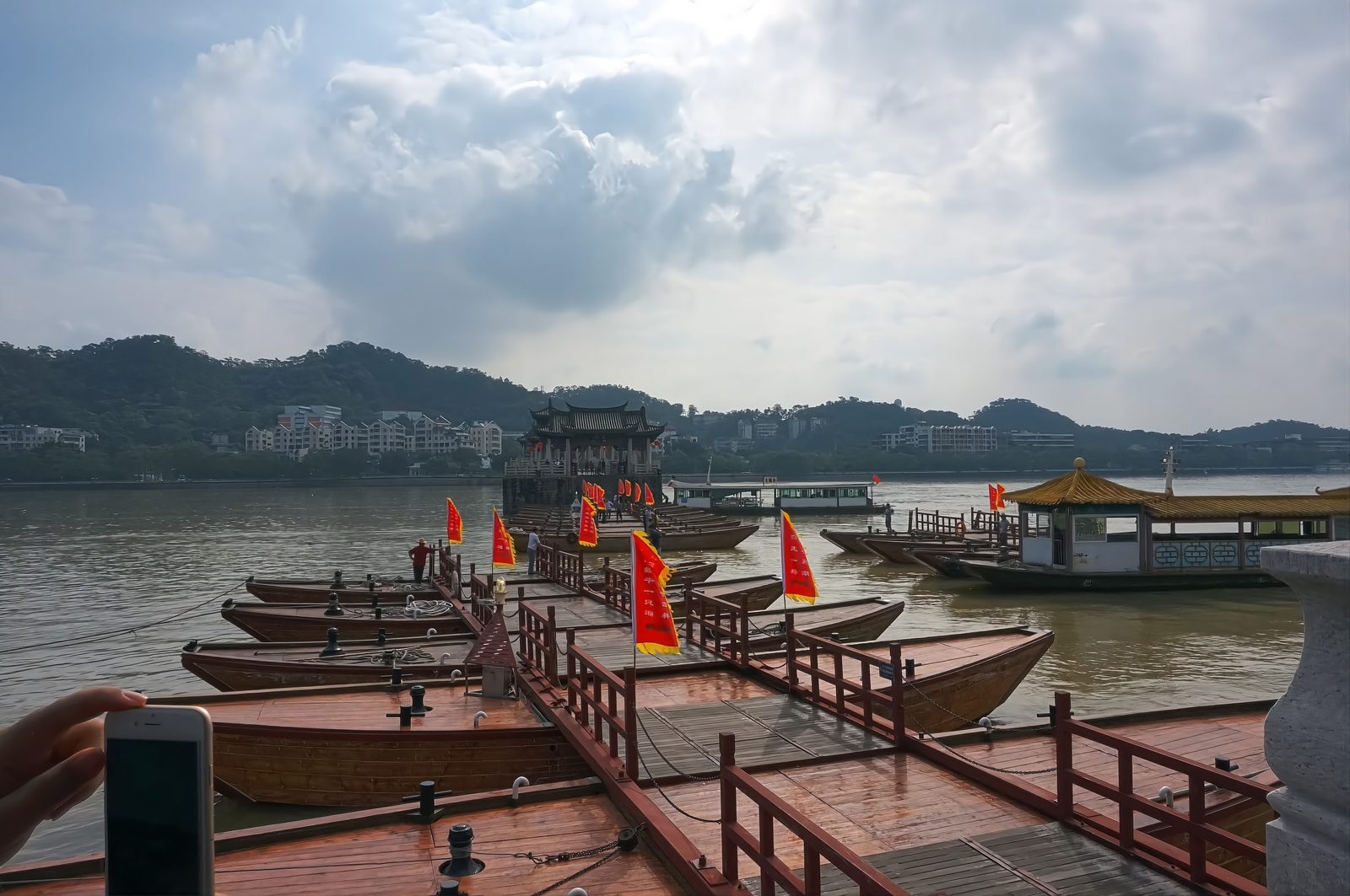 The floating section of Guangji Bridge: eighteen wooden shuttle boats chained bow to stern into a walkway, red flags flying, a stone pavilion beyond