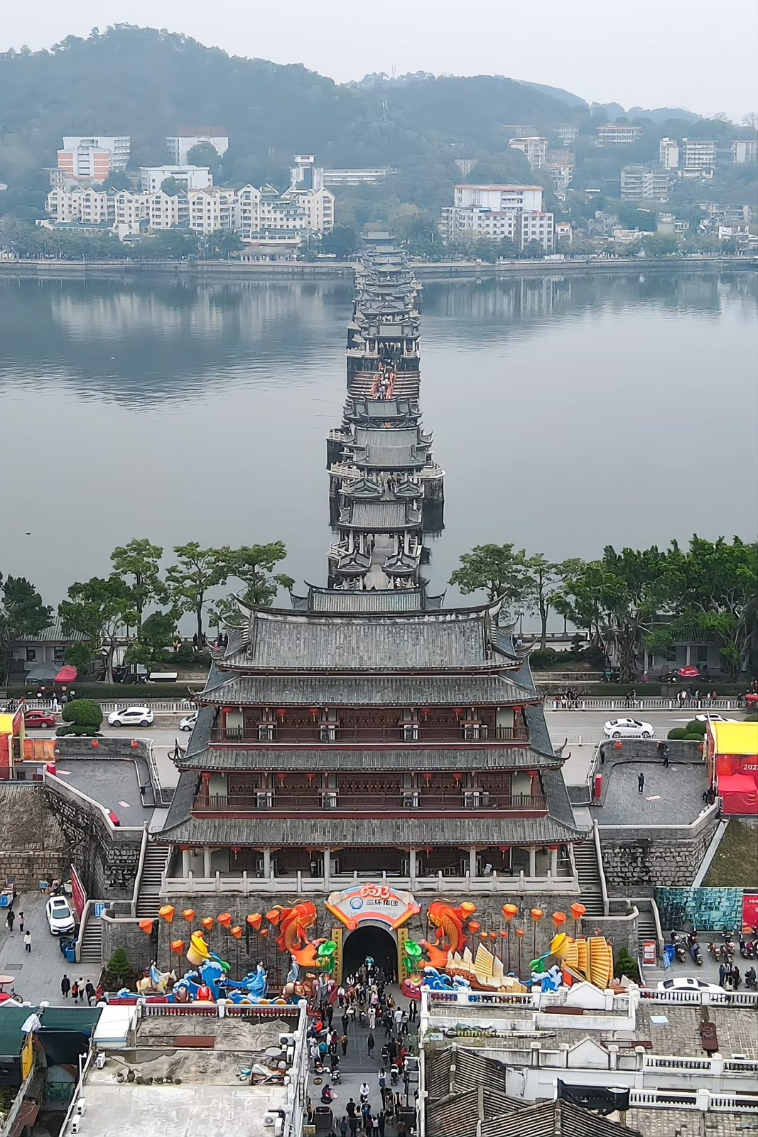 Aerial view from above the Guangji Gate tower: the three-storey gate below, the bridge running away behind it across the Han River to the wooded far bank