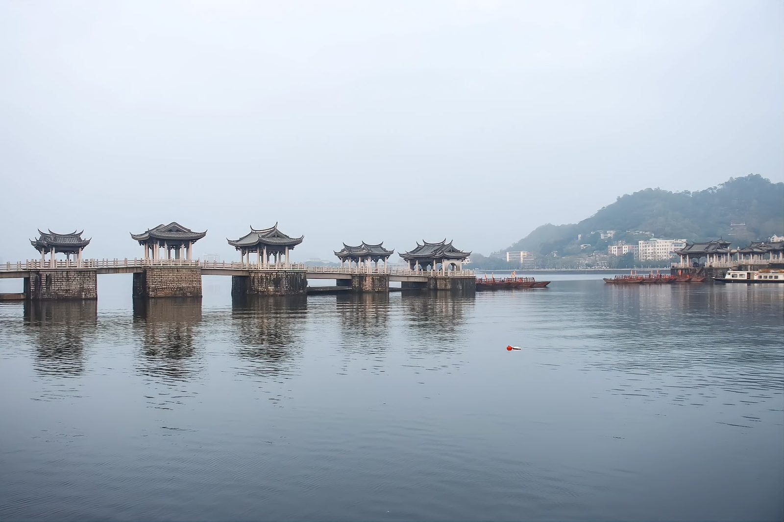 Stone piers of Guangji Bridge standing in the river, each carrying a tiled pavilion, seen along the span