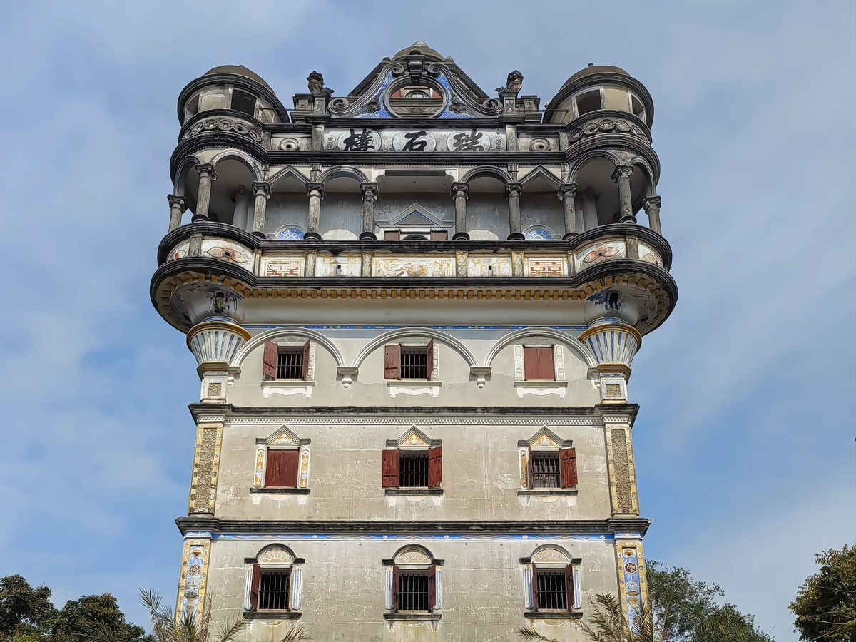 The Jade Stone Tower, Ruishi Lou: a tall nine-storey tower with Roman arches, Ionic columns, domed turrets and a Baroque gable, flanked by young palm trees