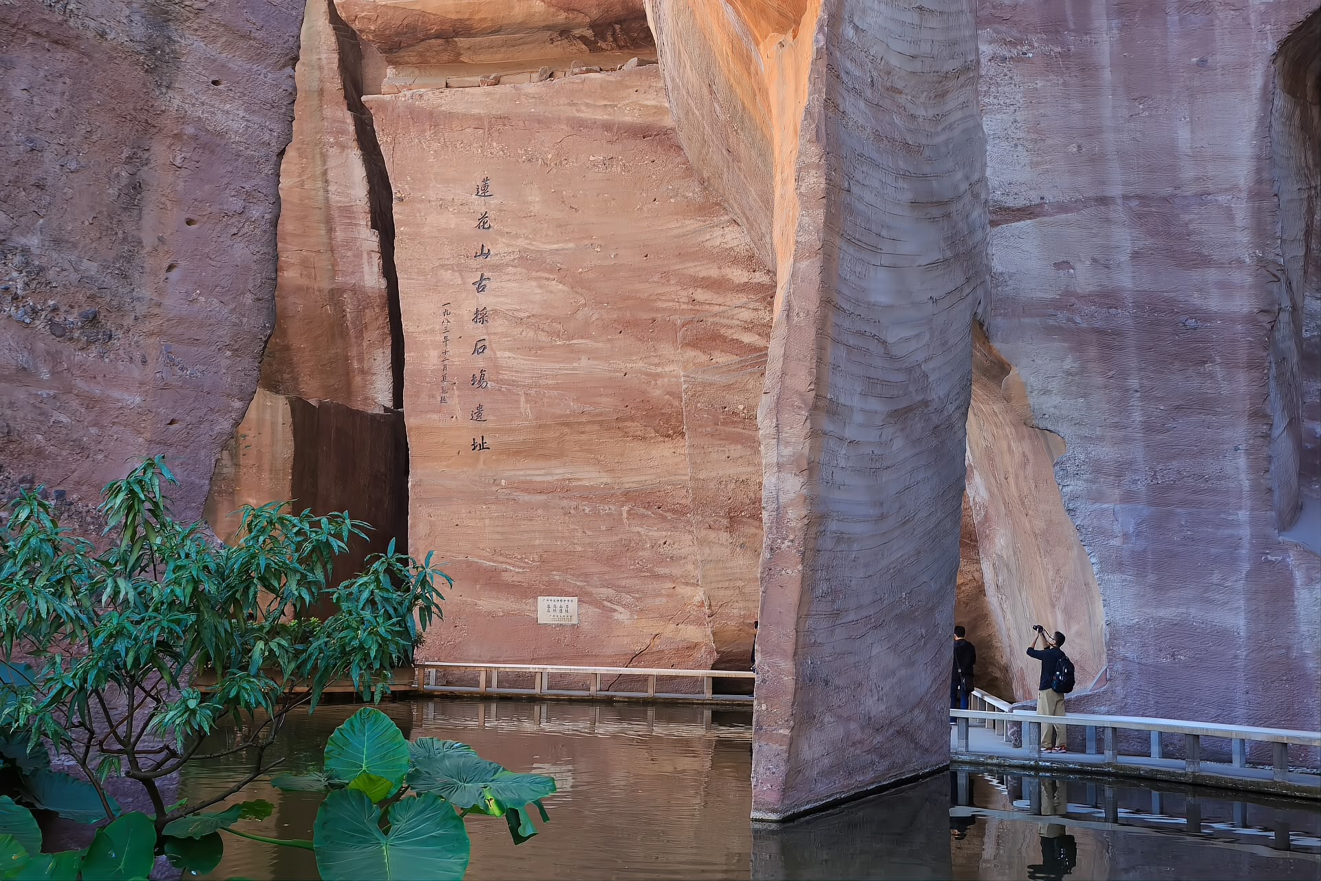 Sheer red sandstone cliff faces and flooded pits of the ancient quarry at Lianhuashan, Panyu