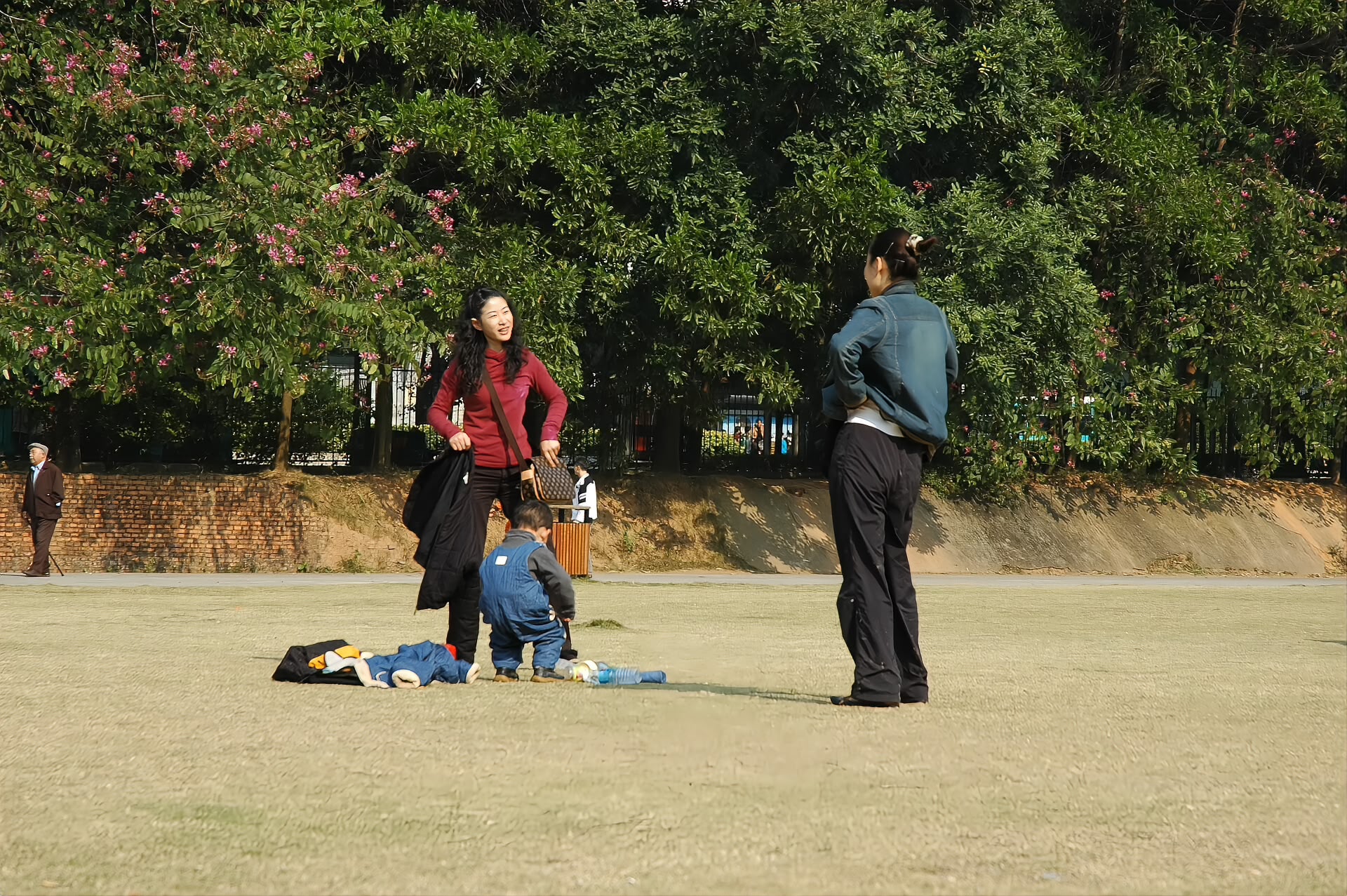 Visitors on the grass at Lianhuashan Park with the Shenzhen skyline behind them