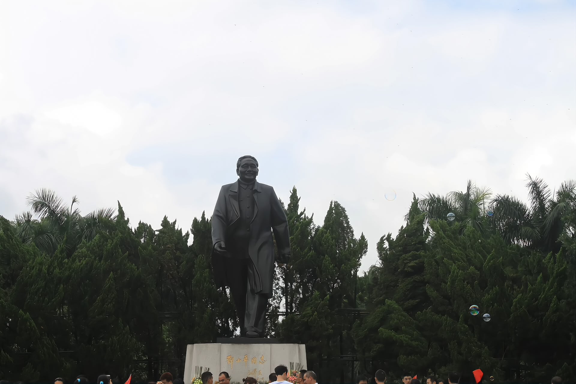 Side view of the bronze Deng Xiaoping statue on the summit square with planted cypress behind