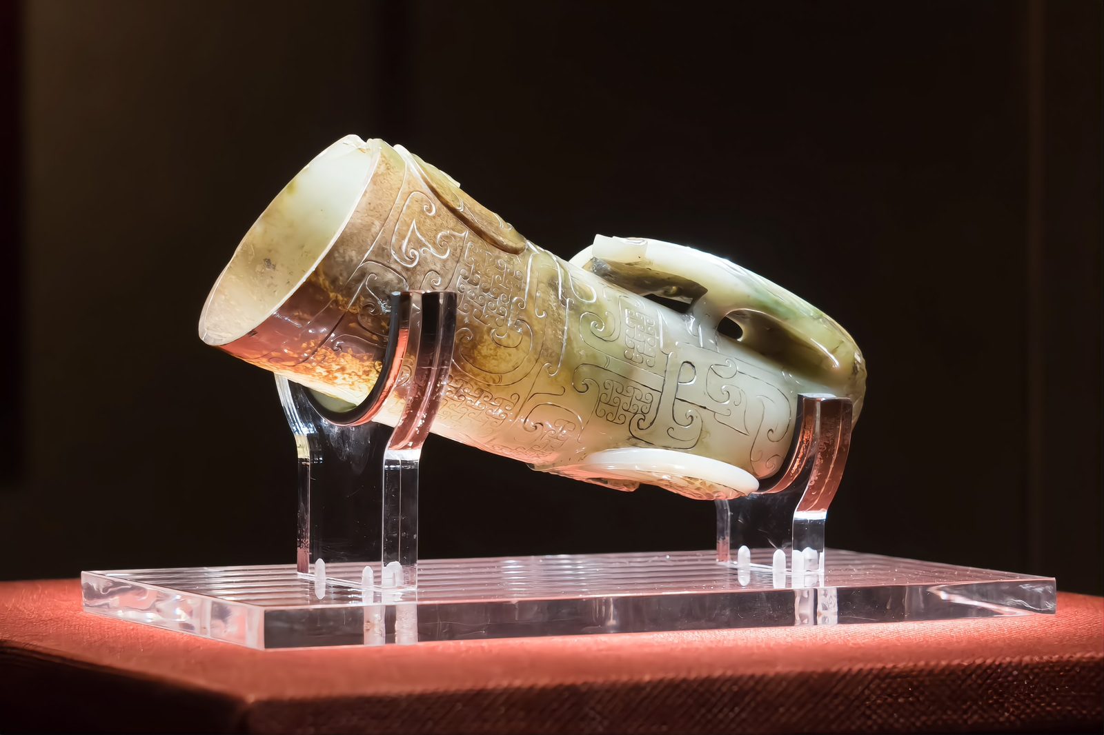 The rhinoceros-horn shaped jade drinking cup on its gilt bronze stand: carved pale green jade in the form of a horn, displayed on a mount in the museum