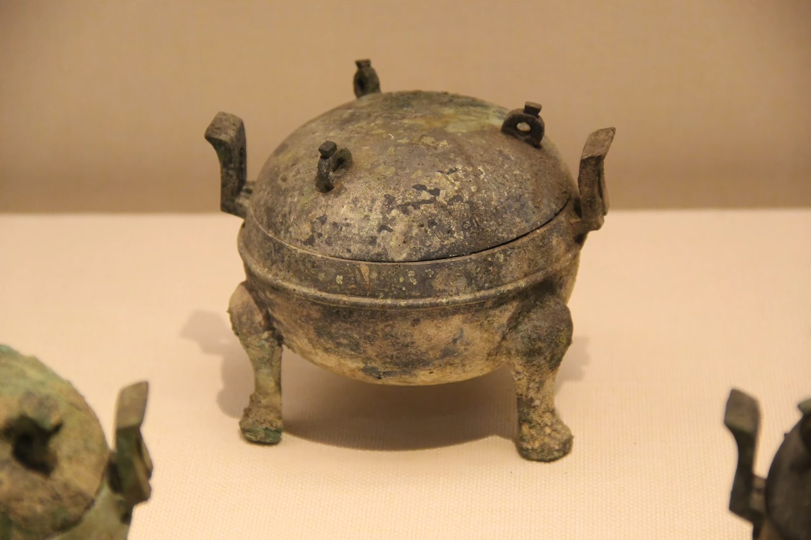 A large bronze tripod ding cooking vessel with a domed lid and three legs, displayed in the Nanyue King Museum