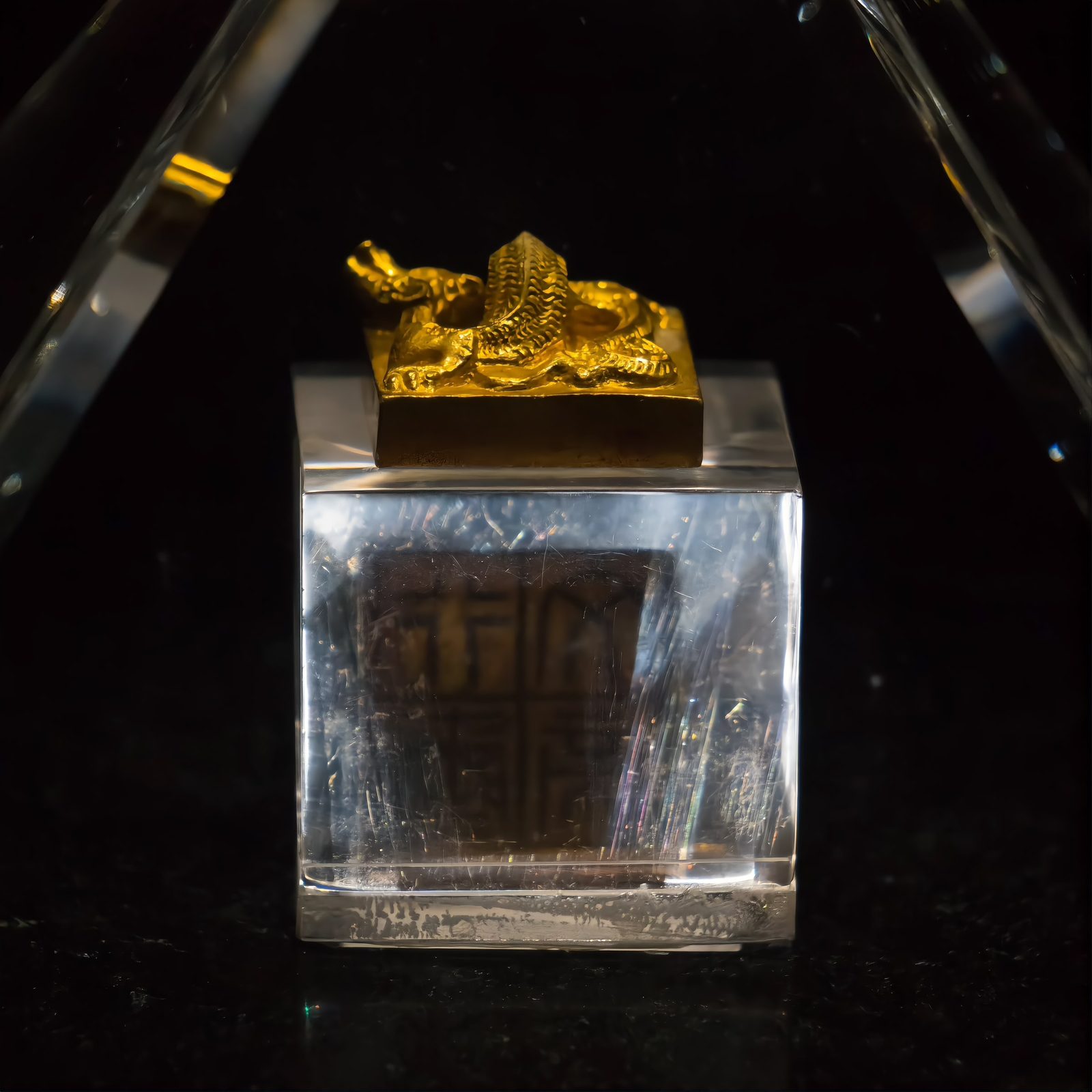 The gold seal of Emperor Wen of Nanyue on a clear acrylic stand: a small square gold block with a coiled dragon forming the knob, casting a shadow on the plinth