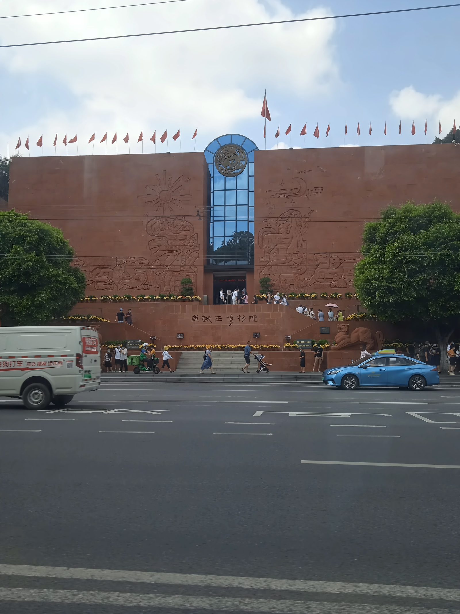 The entrance front of the Nanyue King Museum mausoleum site on Jiefang North Road: a red brick building with a tall glazed central hall rising above the trees, street in front
