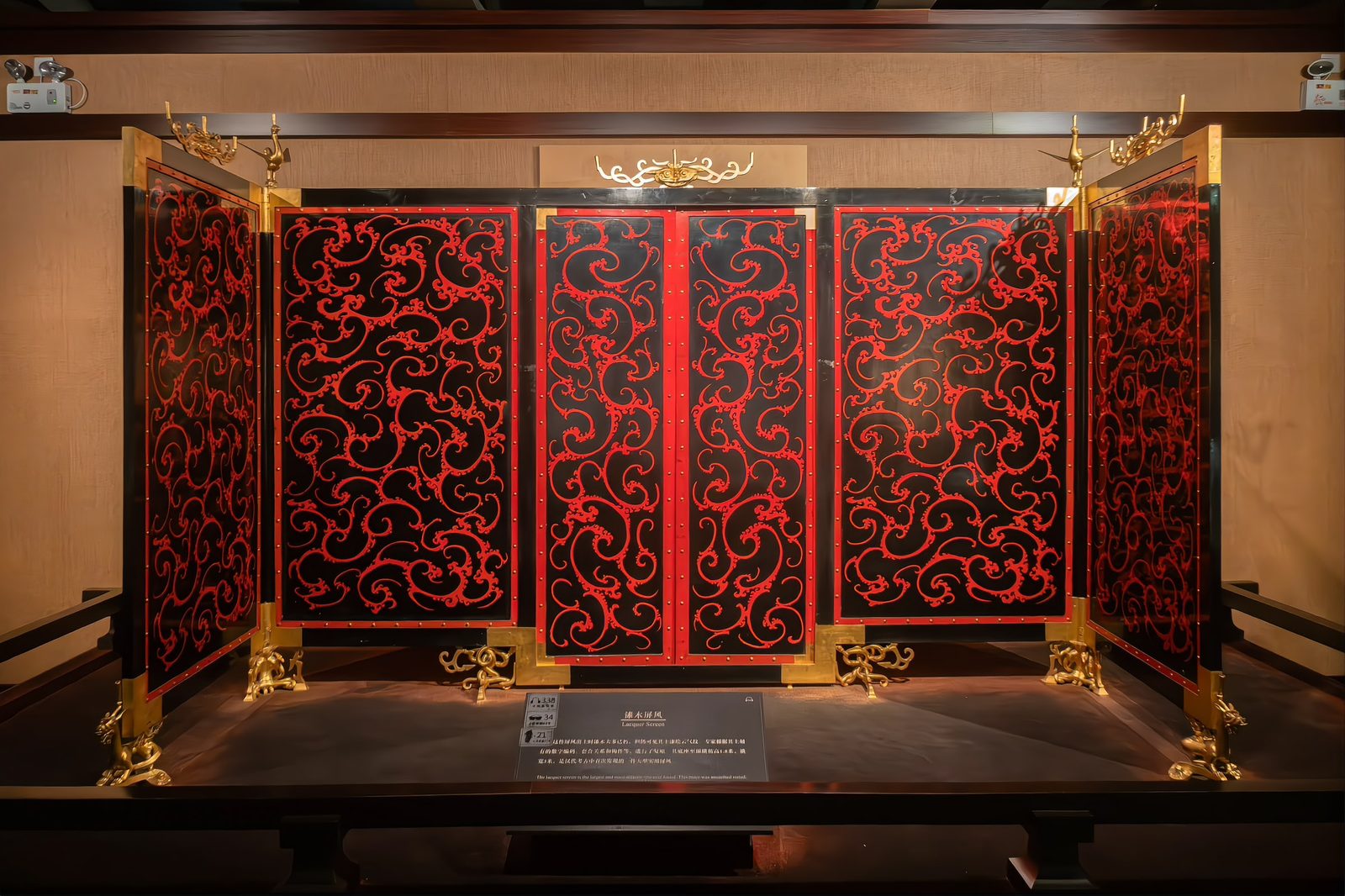 A reconstruction of the lacquered bronze screen from the tomb's front chamber: red and black lacquer panels with gilt bronze fittings, standing full height behind a barrier