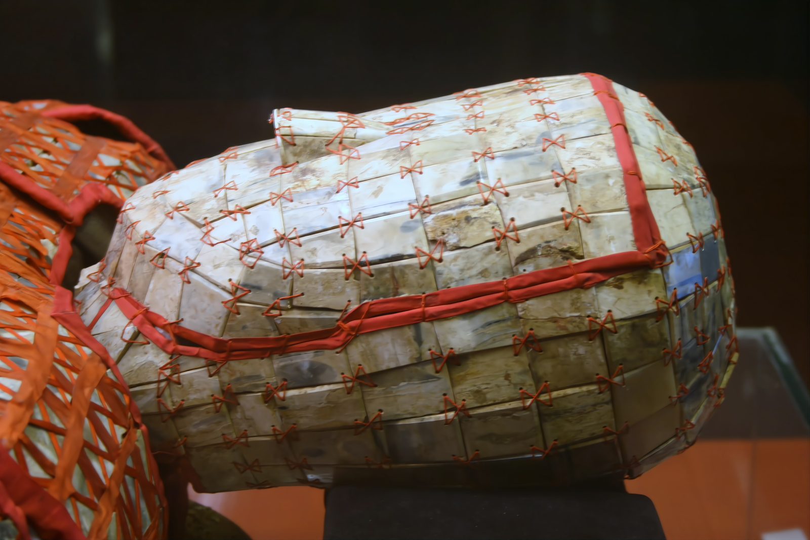 A close view of the jade burial suit's head covering: small jade plaques tied with red silk ribbon in figure-eight crosses, the mask-shaped head cover clearly visible