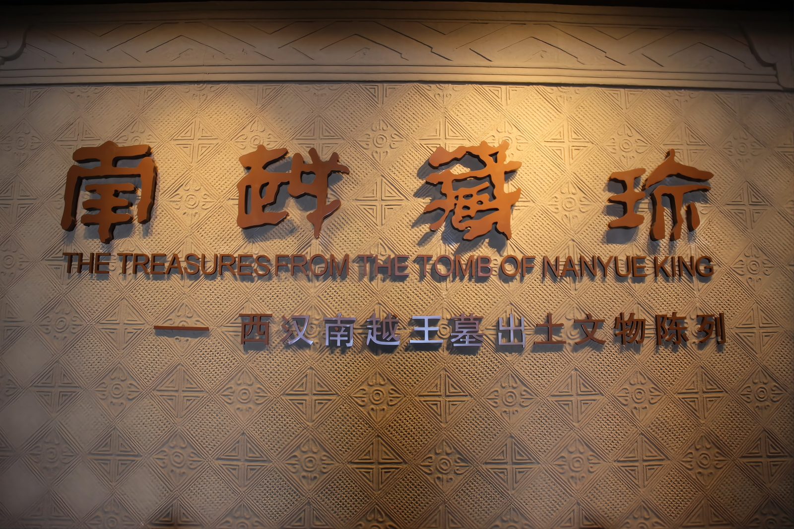 The inscription wall inside the Nanyue King Museum exhibition hall: large gilded Chinese characters reading Nanyue Cang Zhen, treasures of Nanyue, above a gallery entrance