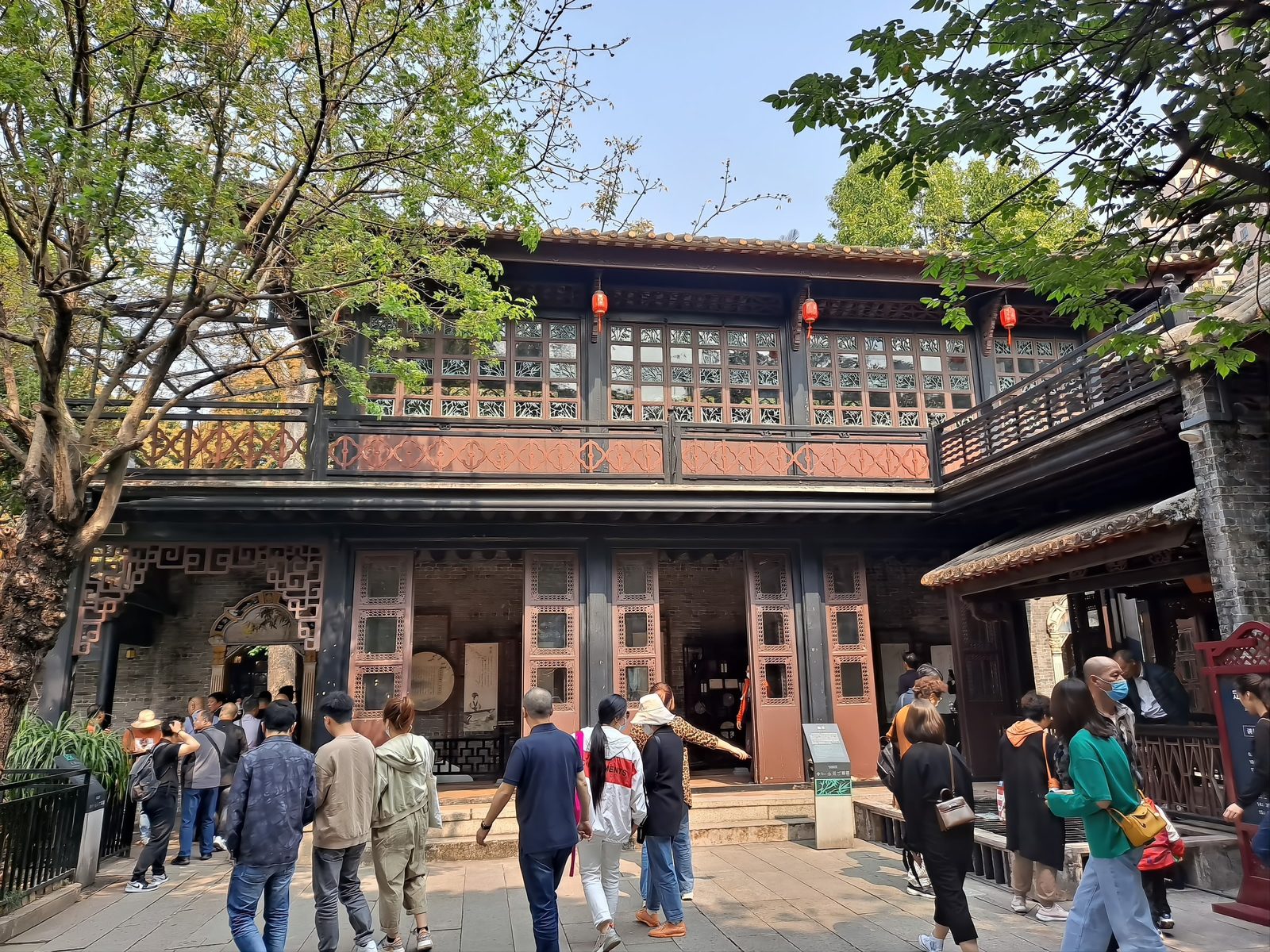 The Boat Hall at Qinghui Garden: a two-storey brick and timber building shaped like a river boat, with wave-pattern railings along the upper corridor, dark timber columns and grey brick walls, visitors at the water's edge