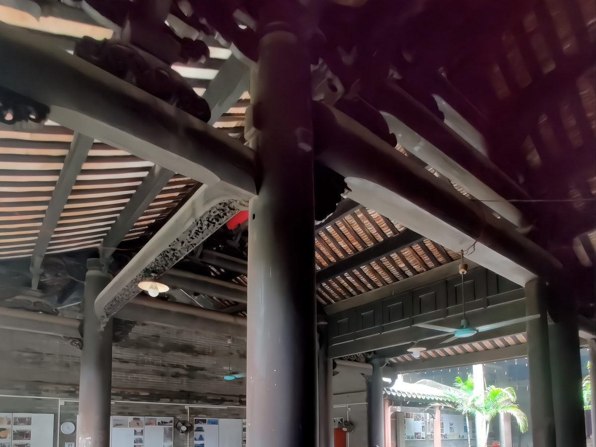 The interior of the Liugeng Hall: giant dark timber columns rising to a tiled roof, with tables and chairs set out below