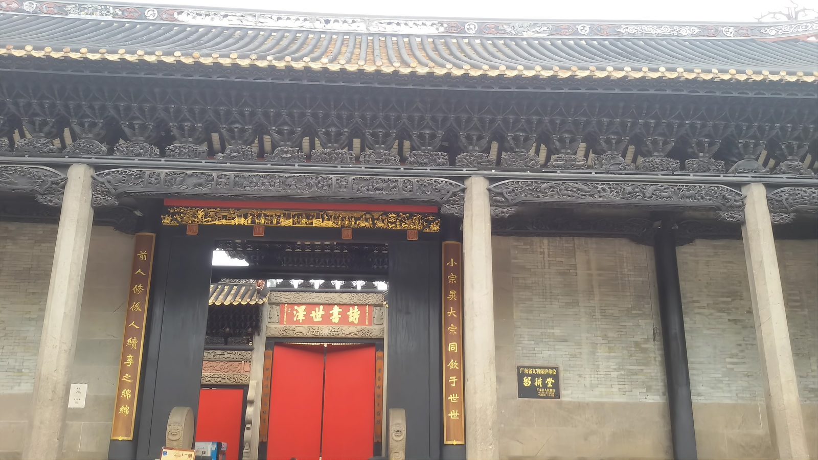 The ceremonial gate of the Liugeng Hall: an ornate stone arch with dark timber brackets, a gold plaque reading A Scholarly Legacy, and red couplets down both sides
