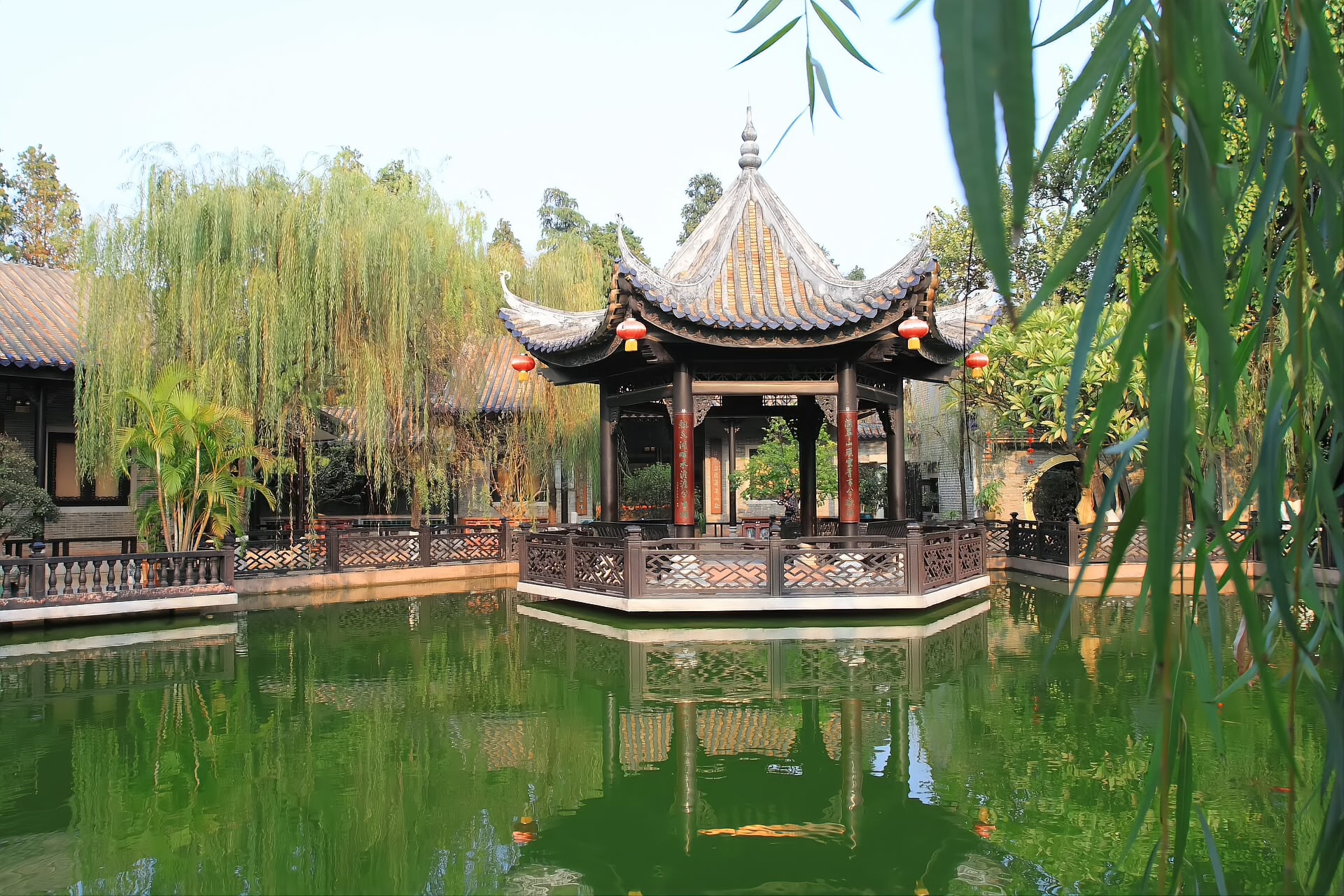 The octagonal pavilion of Yuyin Shanfang standing in its pond, willows behind
