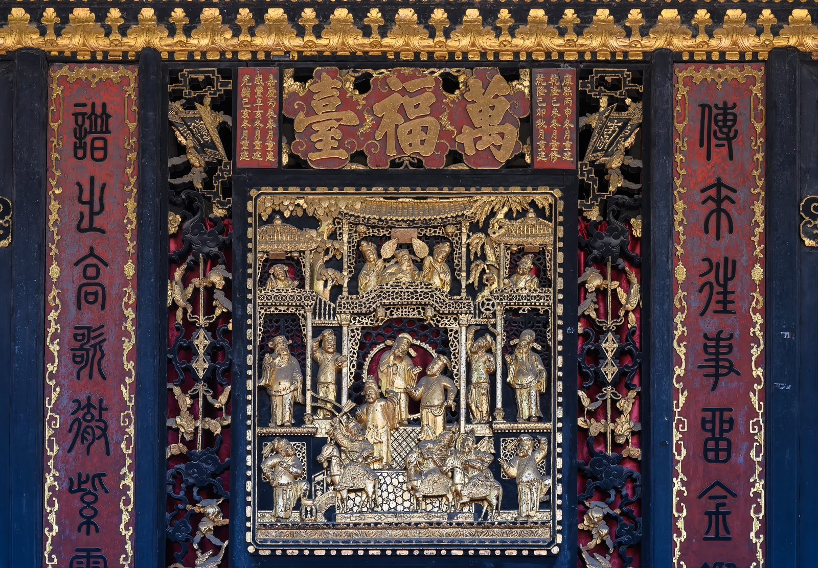Close view of the Wanfu Stage's carved gilt panel with its name board reading Wanfu Tai in gold characters on red